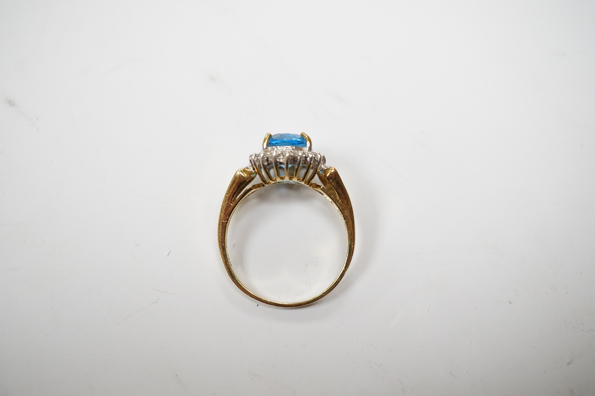 A modern 14k and oval cut blue topaz set dress ring, bordered with diamonds, size R, gross weight 4.7 grams. Condition - fair to good.